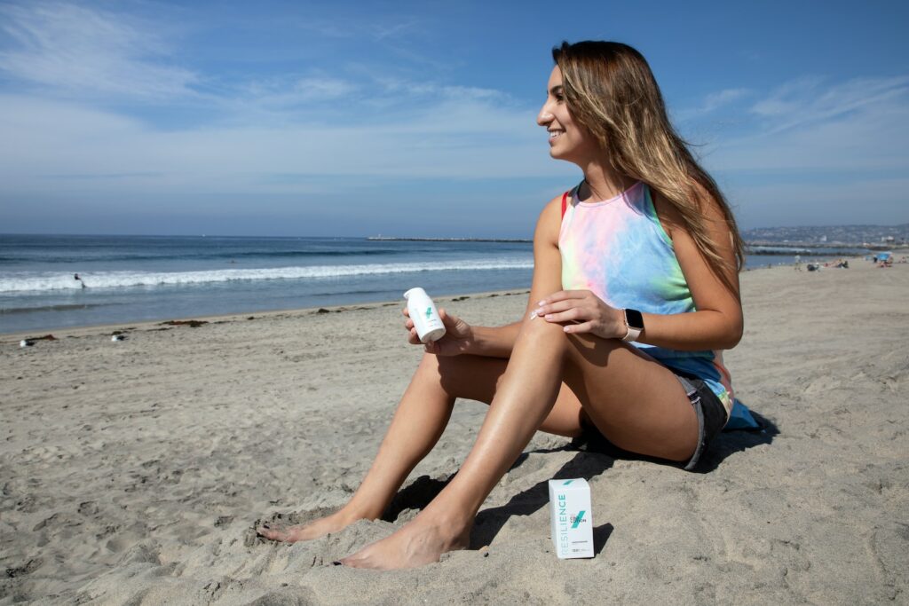 woman in blue and pink tank top sitting on beach shore during daytime