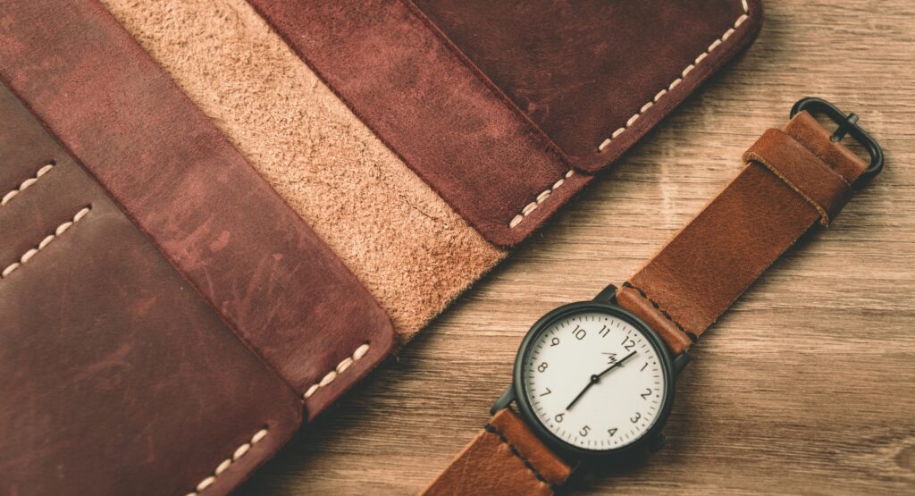 a watch sitting next to a wallet on a table