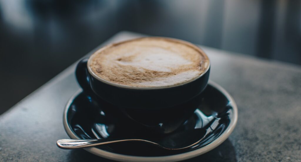 photo of black teacup filled with coffee on saucer