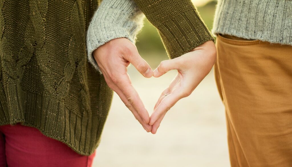 person forming heart shape with their hands