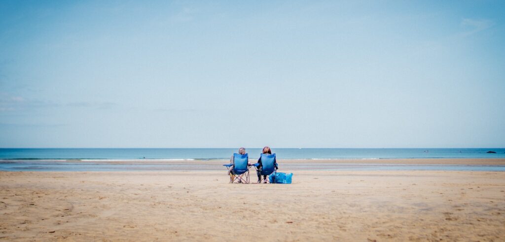 2 person sitting on beach sand during daytime