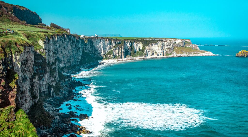 white rock cliff beside body of water'