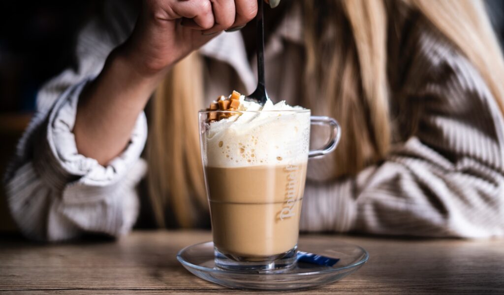 person holding clear glass mug with brown liquid