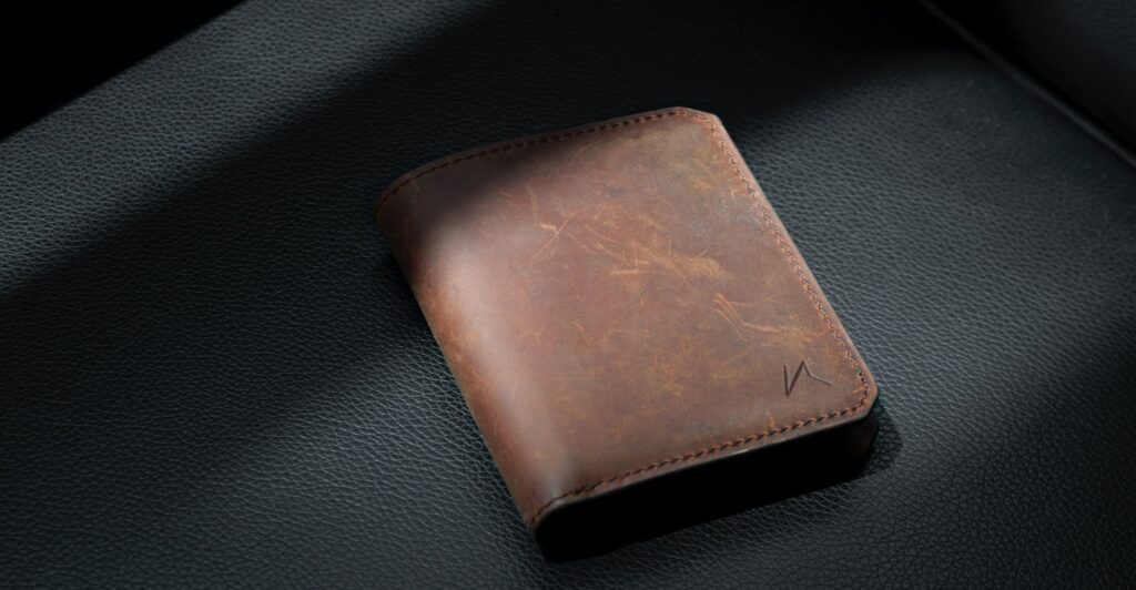 brown leather bifold wallet on black leather textile