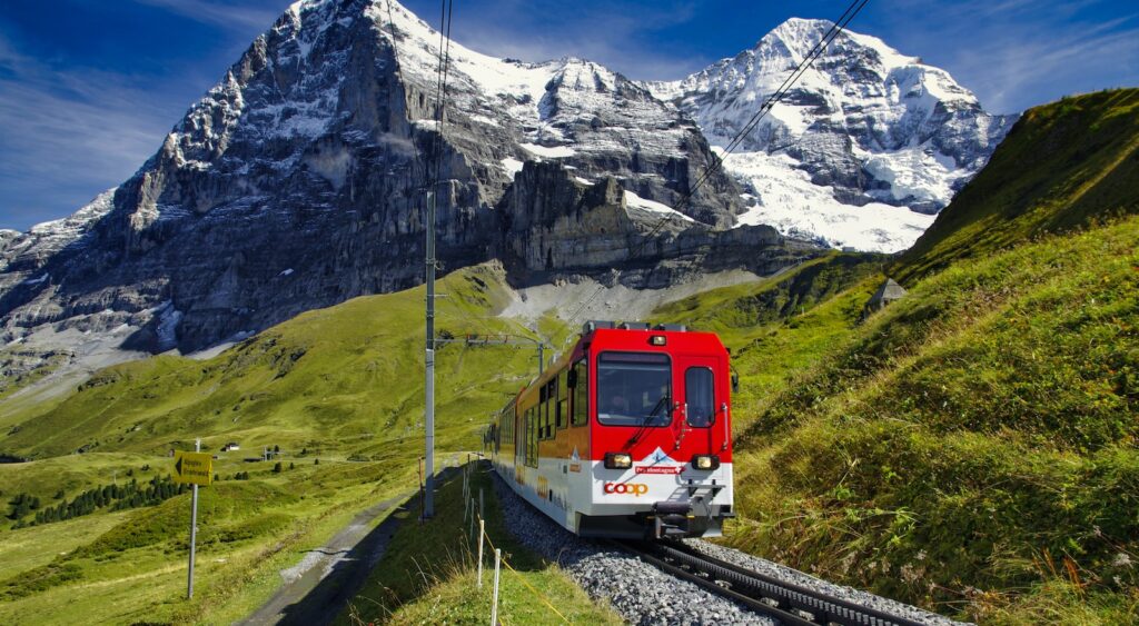 red and white train on rail road near snow covered mountain during daytime