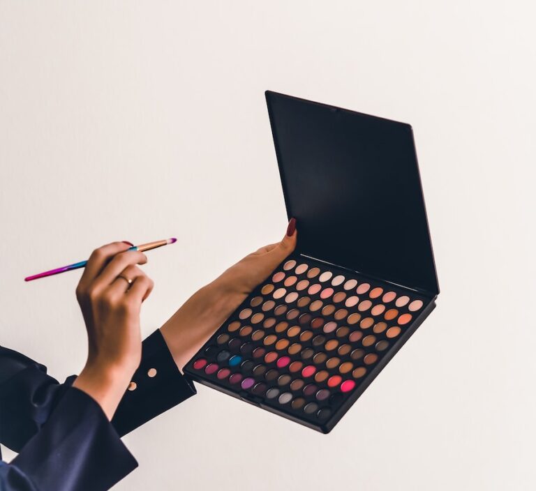 a person holding a makeup palette and a pencil