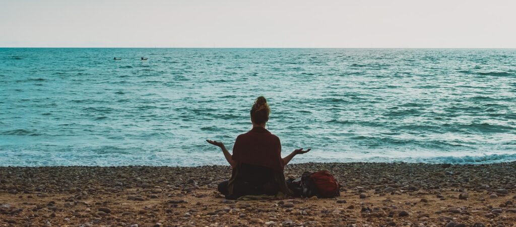 person doing yoga on seashore during daytime