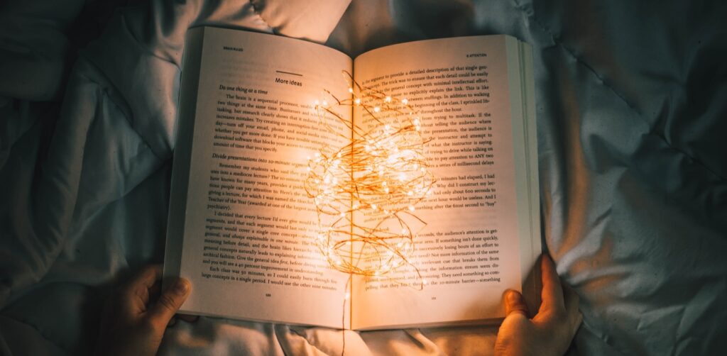 person holding string lights on opened book