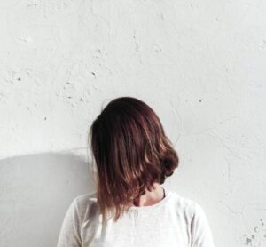 woman in white shirt leaning on wall during daytime