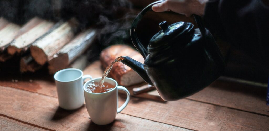 person pouring tea on white ceramic mug