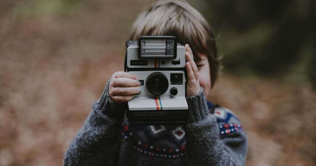 boy using white and black instant camera