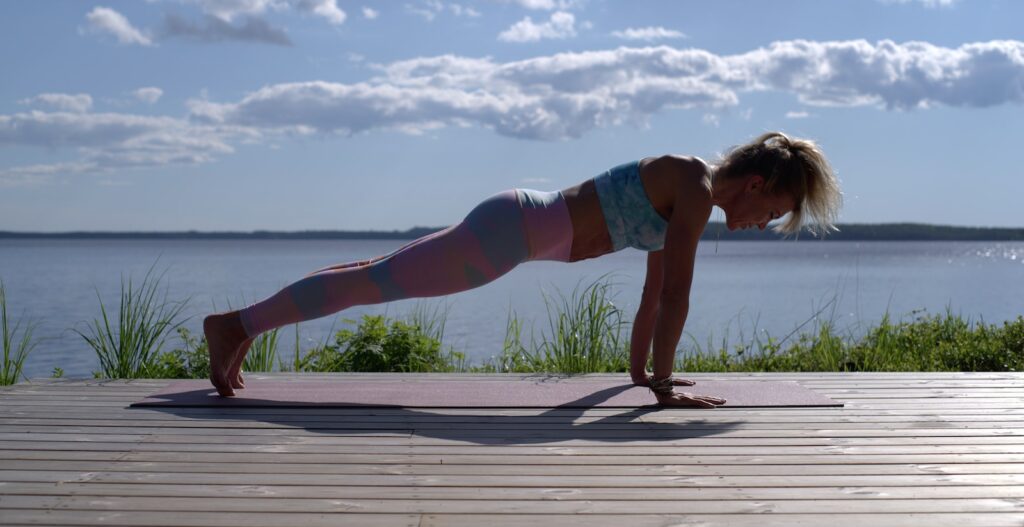 woman in blue sports bra and blue denim shorts standing on wooden dock during daytime