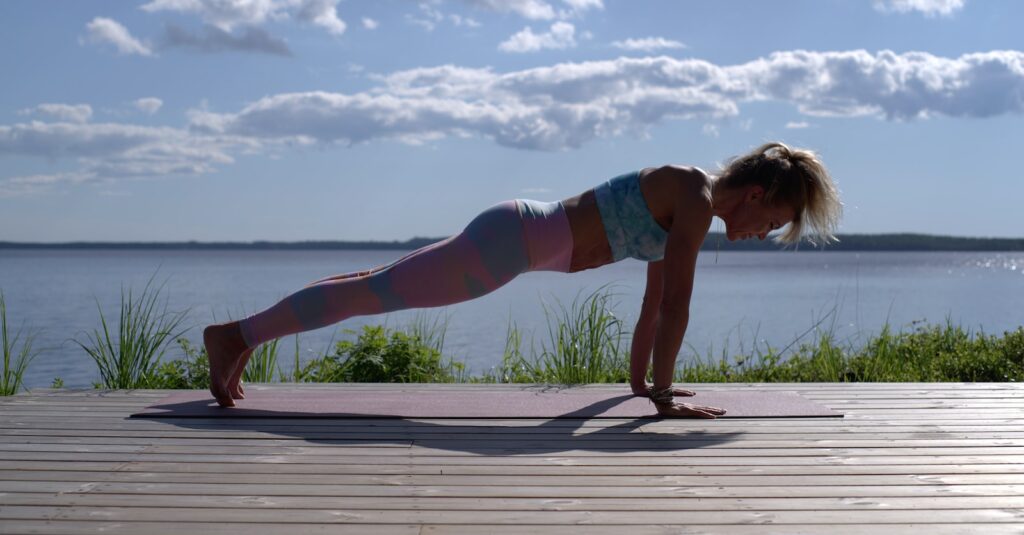 woman in blue sports bra and blue denim shorts standing on wooden dock during daytime