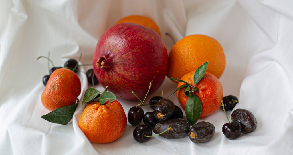orange fruit and black berries on white textile