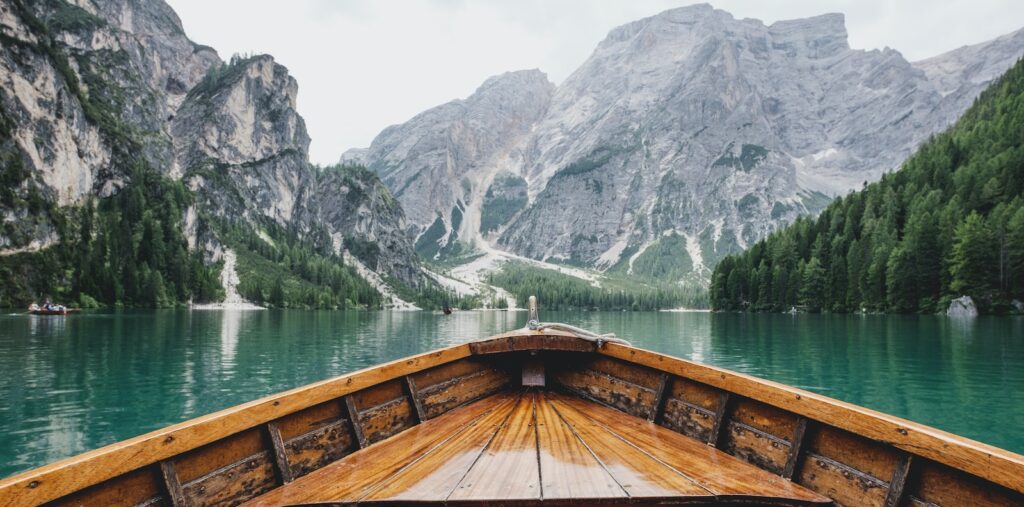 brown wooden boat moving towards the mountain