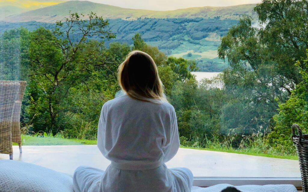 sitting woman in white robe looking at mountains during daytime