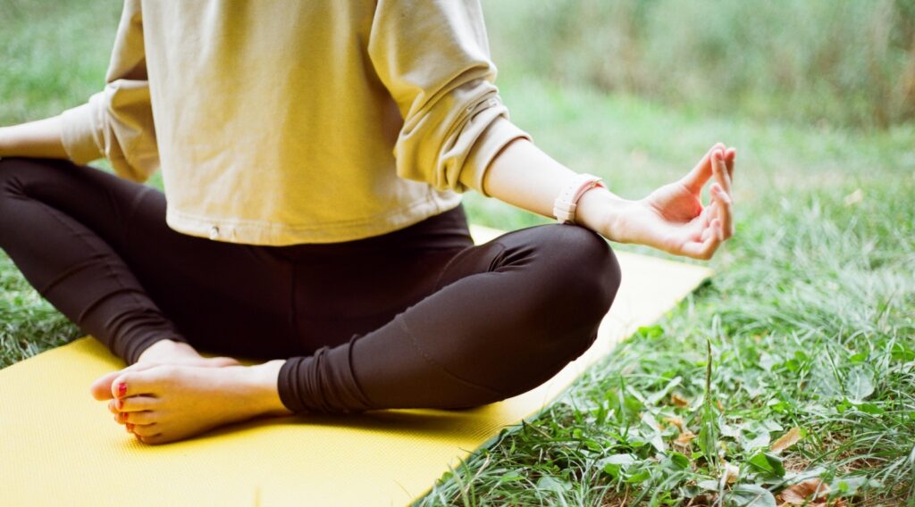 woman in brown long sleeve shirt and black pants sitting on white textile