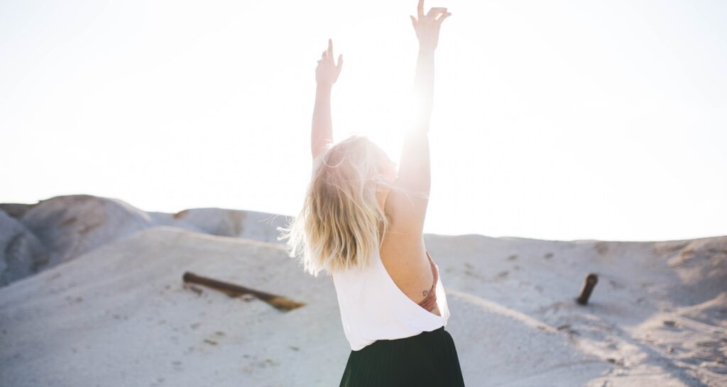 woman standing on the desert while her hands up