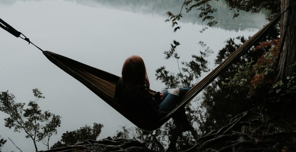 woman sitting on hammock while facing backwards