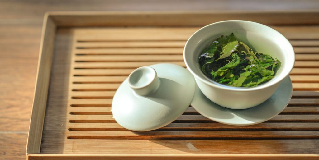 green tea leaves in white ceramic bowl with open lid