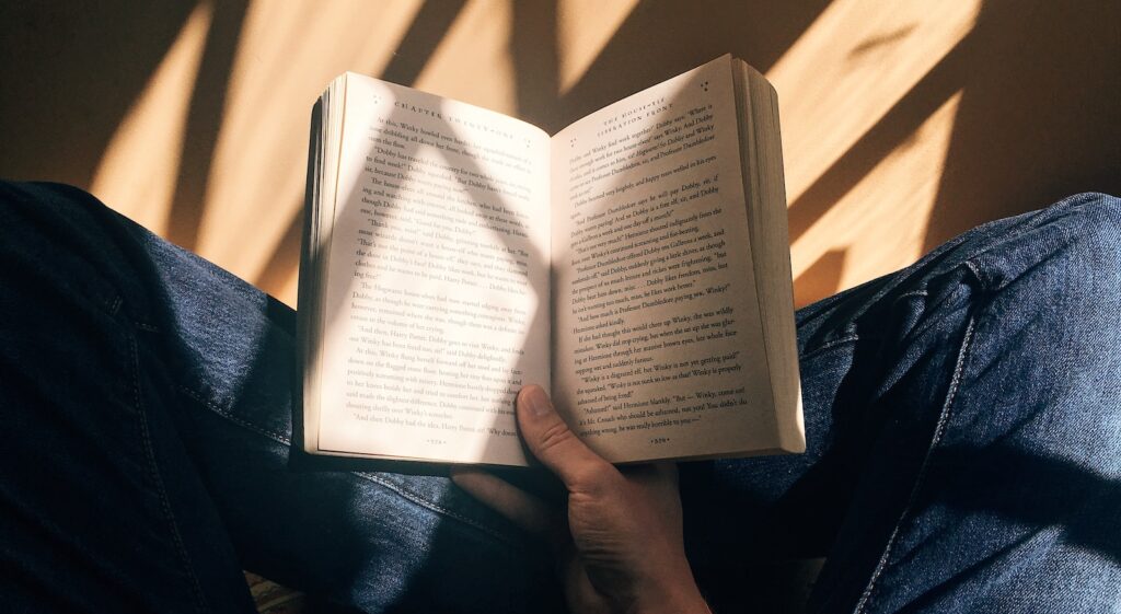 person holding book sitting on brown surface