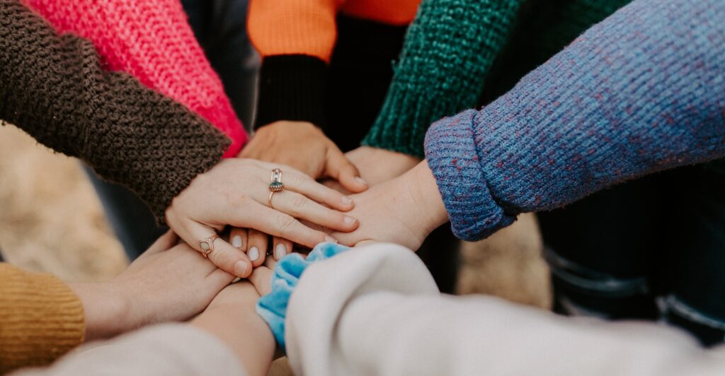 person in red sweater holding babys hand