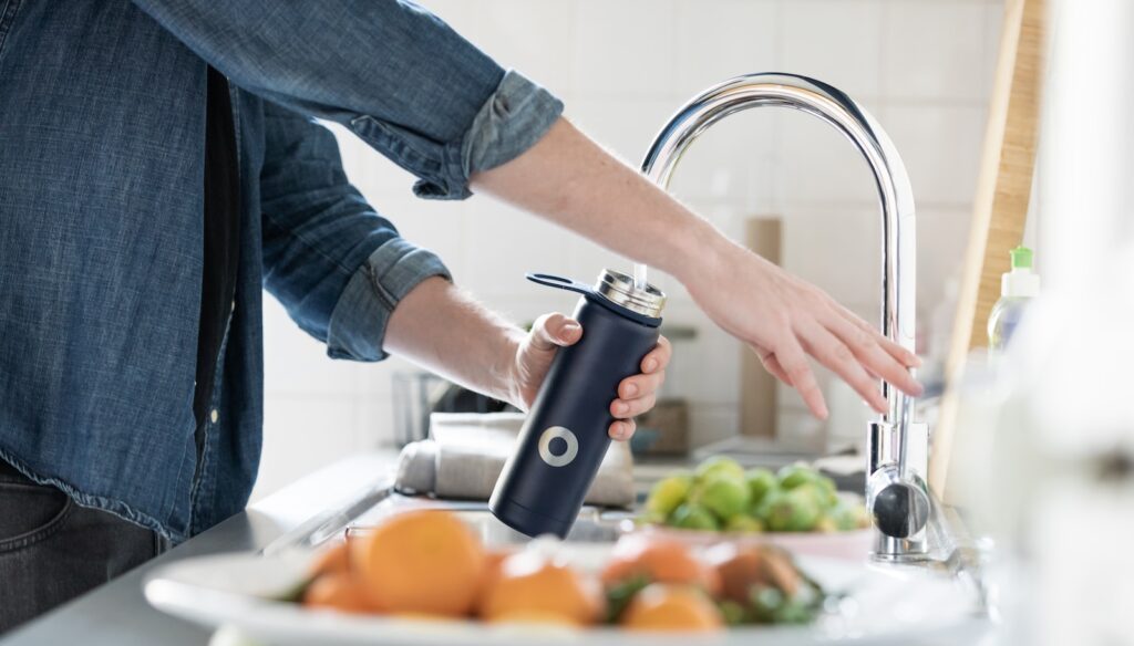 person in blue denim jacket holding stainless steel bottle