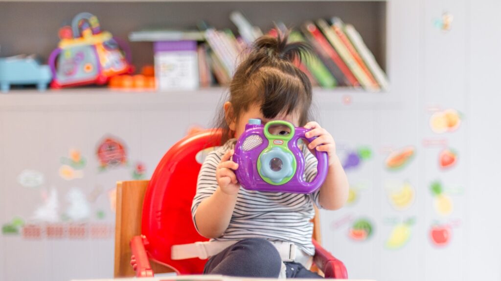 girl holding purple and green camera toy