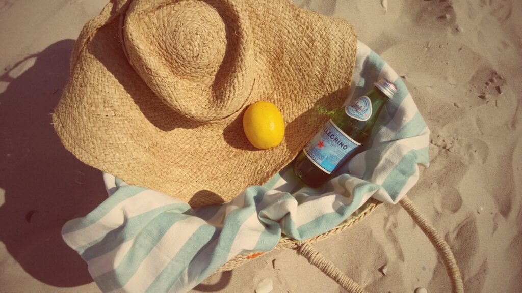 a hat and a bottle on a towel on the beach