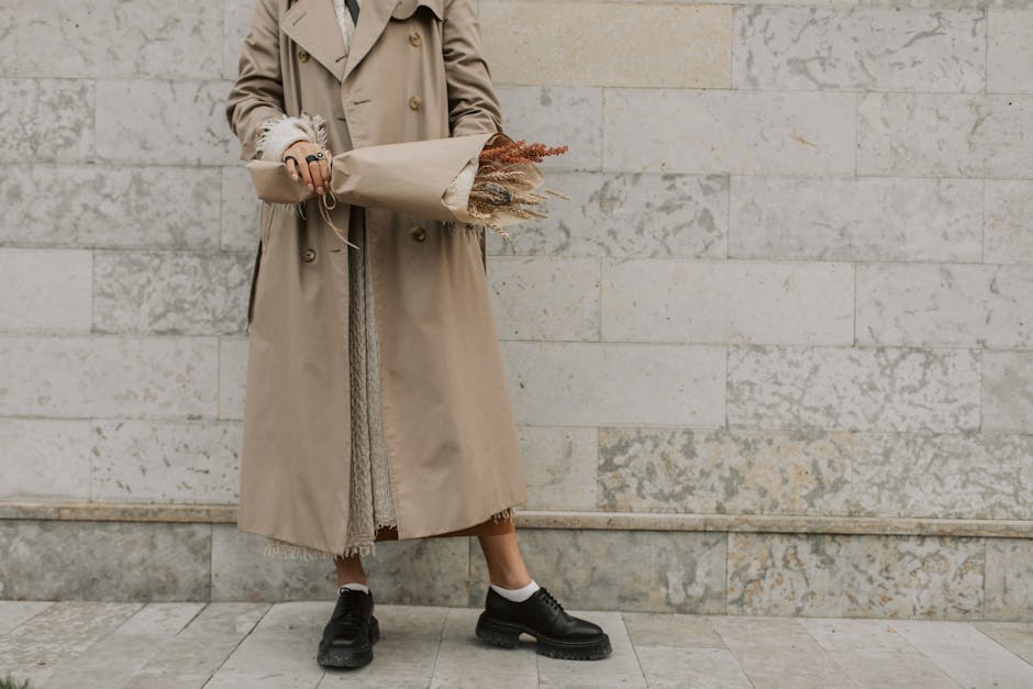Alt text: Beige trench coat layered over white summer dress as transitional layered neutrals outfit
