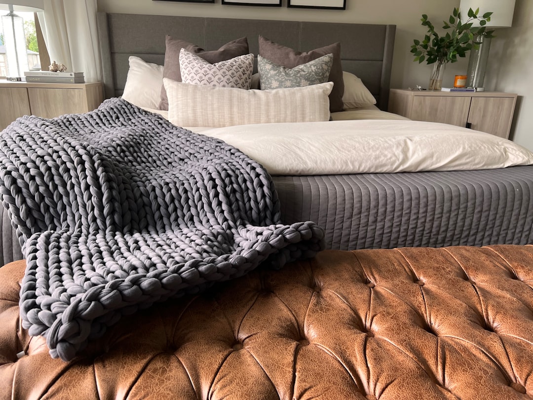Chunky knit throw overlapping rust velvet and sage linen pillows on a light gray sofa