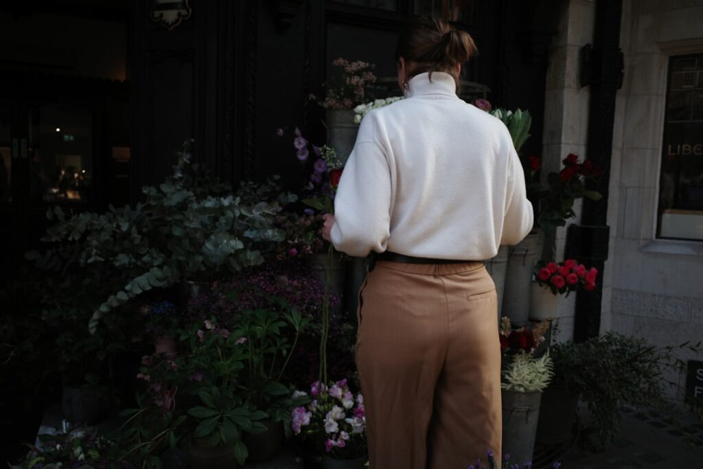 Alt text: Woman in layered neutrals including cream sweater and tan trousers for fall transition