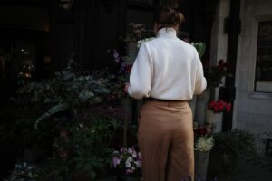Alt text: Woman in layered neutrals including cream sweater and tan trousers for fall transition